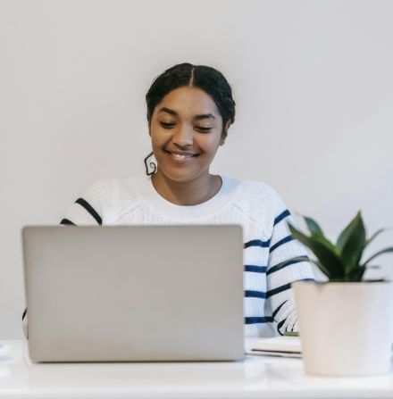 Ethnic lady working remotely on netbook at table in room